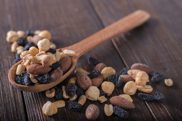 Dried fruits with nuts in a wooden spoon. Wooden background.