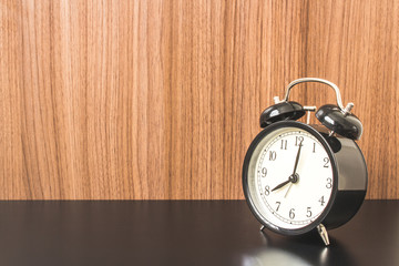 Wooden Background with Alarm clock on Black table.