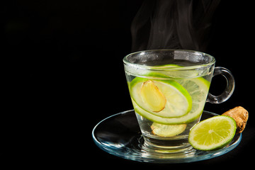 Steaming hot lemon and ginger water isolated on black background
