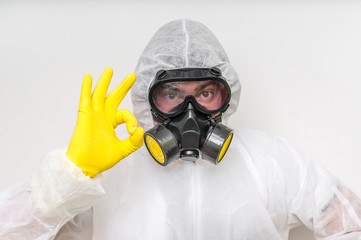 Man in coveralls with gas mask is showing O.K. symbol