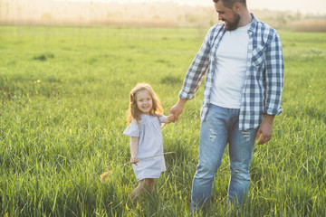father and daughter walking in high grass field