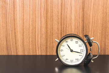 Wooden Background with Alarm clock on Black table.