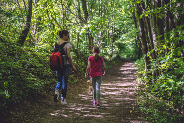 Obraz premium Mother and daughter walking on path in woods