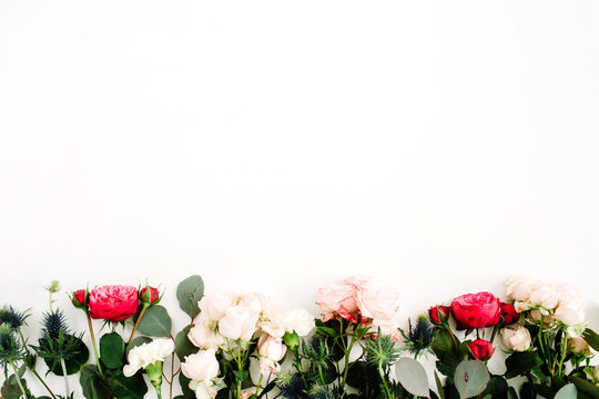Red and beige rose flowers, eringium flower, eucalyptus branches and leaves on white background. Flat lay, top view. Floral background