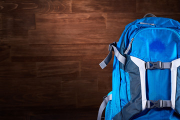 Tourist blue backpack against wooden background.