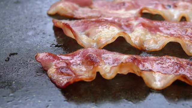 Close-up of a slice of bacon fried on a hot grill
