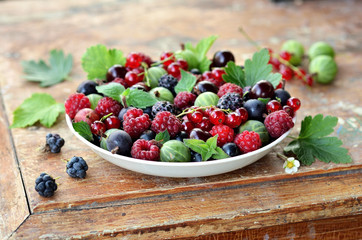 Garden berries in a bowl on wooden table