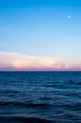 Clouds and moon in sunset sky over sea