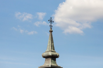 Fototapeta na wymiar Christian cross at the top of a steeple church tower, typical Austro Hungarian baroque style of an Orthodox church of Serbia..
