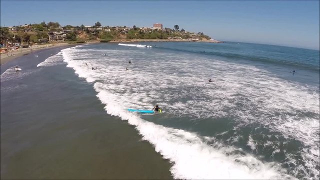 Aerial drone view of surfing at a beach in Chile
