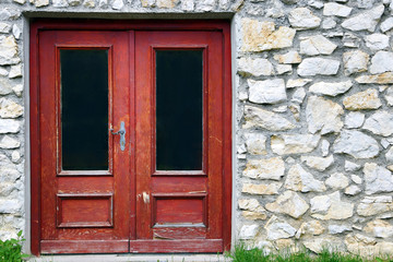 Eine alte rote Holztür im steinernen Haus