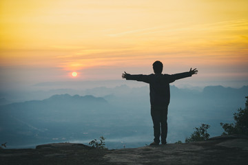 A man standing on the rock in the morning with sunrise and mountain.