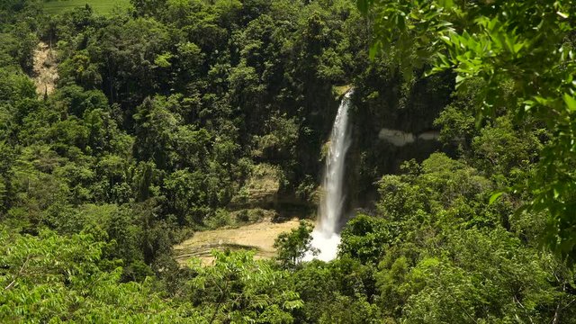 Tropical waterfall in green forest in jungle. Waterfall with natural swimming pool in a mountain river canyon. Philippines, Bohol. 4K video.