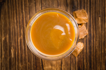 Caramel Sauce on wooden background (selective focus)