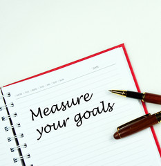 Communication message motivation concept with " measure your goals " word on notebook.