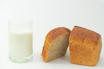 Milk in a glass on a light background with fresh crusted bread.