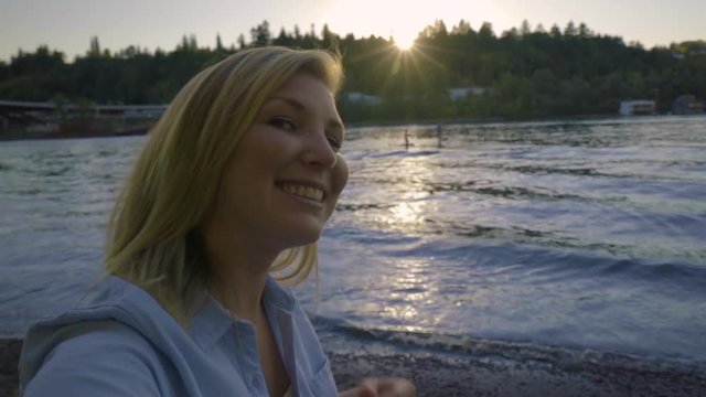 Young Woman Uses Camera Like A Smartphone To Take Selfies At Sunset With Water In Background