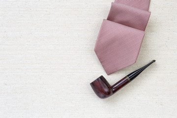 Red pattern necktie with classic wooden pipe on canvas background, father's day background concept, men fashion