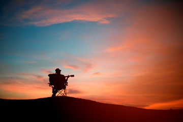 Silhouette of asia young man with playibg acoustic guitar, sunset background
