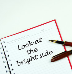 " look at the bright side " words   on note book with pen