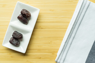 Dates or kurma in white plate over wooden background