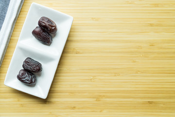 Fototapeta premium Dates or kurma in white plate over wooden background