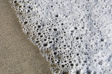 Foam from waves washes up on bech in  coastal California