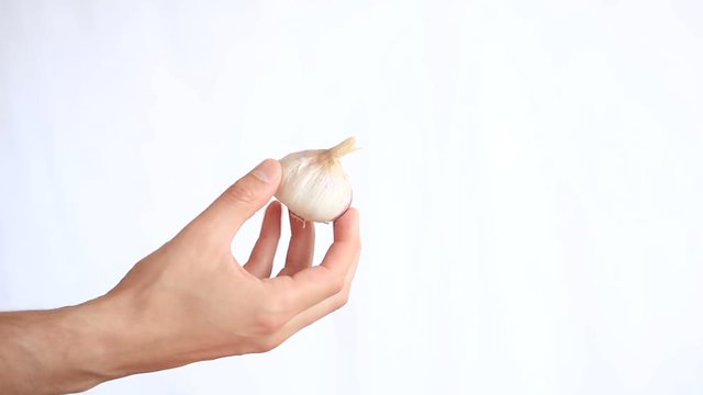 A man's hand holding a vegetable on a white background. garlic