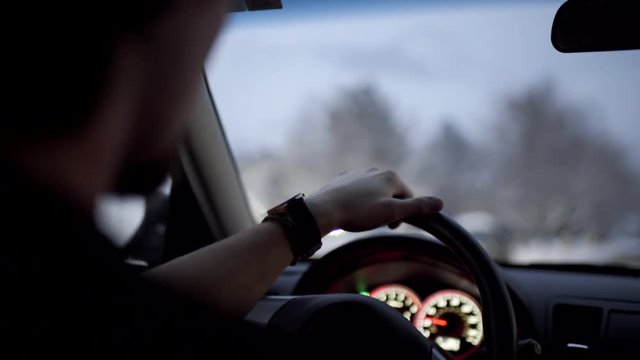 Interior Shot Of Man Driving Down Snowy Road In The Evening, Dashboard Lights On 