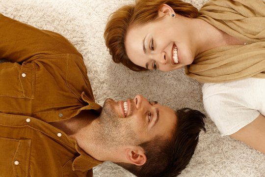 Happy couple lying on carpet