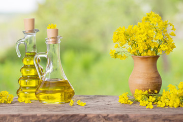 rapeseed oil (canola) and rape flowers on wooden table