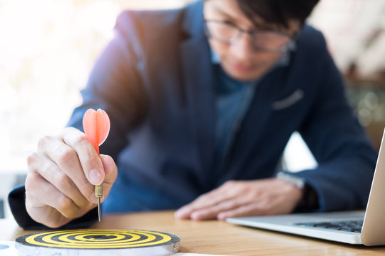 Business Man hand holding a target with darts hitting the center. Concept of personal coaching success. Concept of objective attainment.