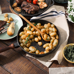 Fried young potatoes in pan with grilled meat
