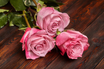 Three beautiful pink roses on wooden table, romantic background
