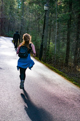 Young girl running in the forest along the asphalt road, sport