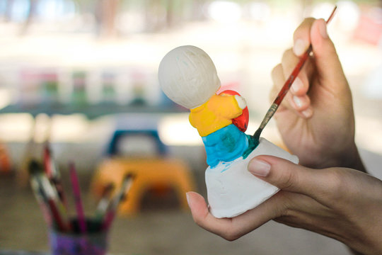 Woman painting color on plaster doll