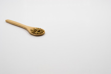 Coriander seed in wooden spoon over white background.