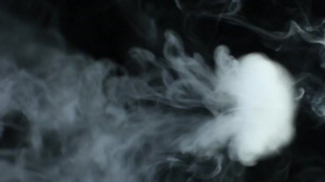 Vapor like smoke on a dark black background. Vape smoke rings in motion at vape clouds.