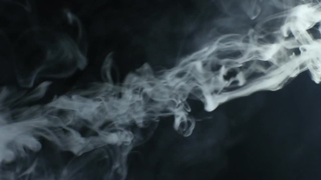 Vapor like smoke on a dark black background. Vape smoke rings in motion at vape clouds.