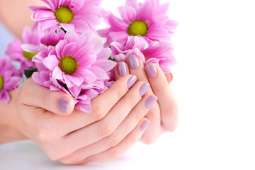 Hands of a woman with pink manicure on nails and pink flowers