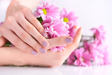 Hands of a woman with pink manicure on nails and pink flowers