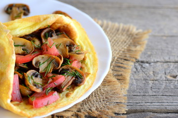 Mushrooms and tomatoes omelet. Homemade omelet stuffed with fried mushrooms, fresh tomatoes and dill greens on a plate and vintage wooden background. Easy vegetarian omelet recipe. Rustic style