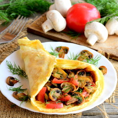 Stuffed omelette on a plate. Homemade omelette with mushrooms slices, tomatoes and dill on a plate, ingredients, fork on a vintage wooden table. Easy and delicious vegetarian breakfast. Rustic style