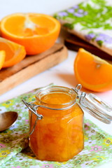 Citrus jam recipe to use up oranges. Homemade orange jam in a glass jar, textile napkin, orange slices on a table. Useful and sweet citrus dessert recipe
