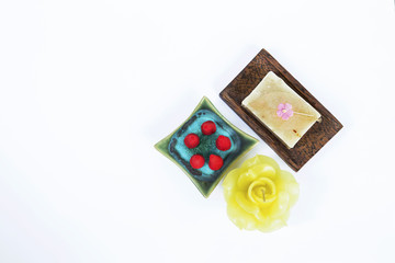 Spa decorate background concept, natural hand soap bar and rose incense cone on green ceramic plate and yellow rose candle on white background