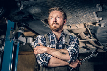 Mechanic holds nut key under the car.