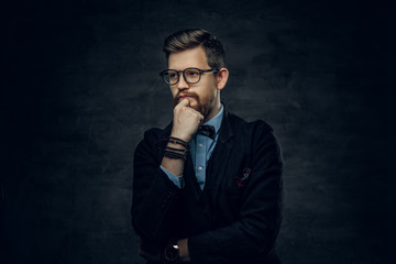 Bearded elegant male in eyeglasses dressed in a dark blue suit with bow tie.