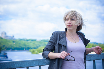 Fototapeta premium Blond head american woman rest after work in city. Citizen girl relax around river and park