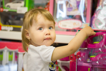 Happy little girl chooses toys in a children's store