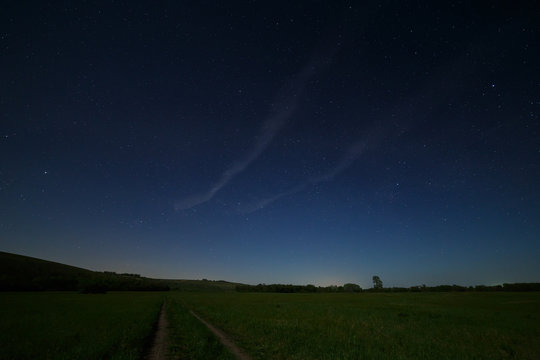 Night starry sky above the road in the countryside.